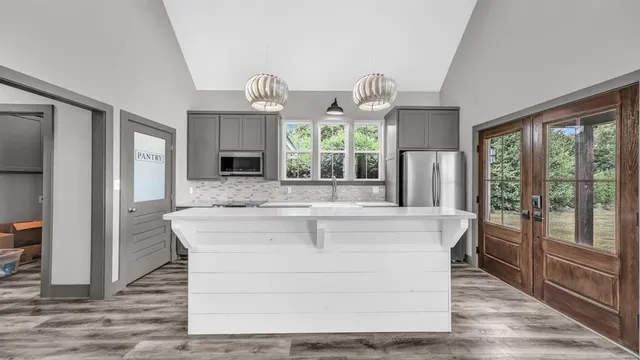 a view of living room kitchen with island stainless steel appliances and wooden floor