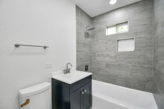 a bathroom with a bathtub shower sink vanity and toilet
