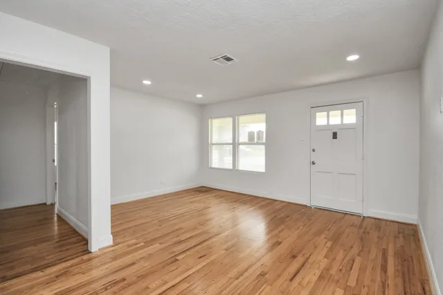a view of an empty room with wooden floor and a window