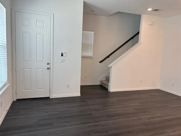 a view of an empty room with wooden floor and stairs