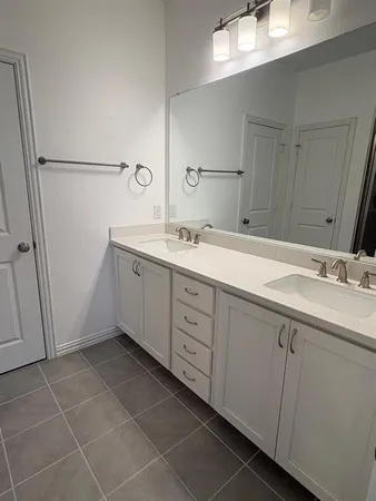 a spacious bathroom with a double vanity sink a mirror and a shower