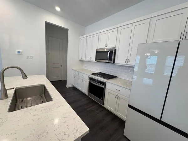 a kitchen with granite countertop white cabinets and stainless steel appliances