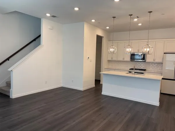 a view of kitchen with granite countertop stainless steel appliances refrigerator and microwave