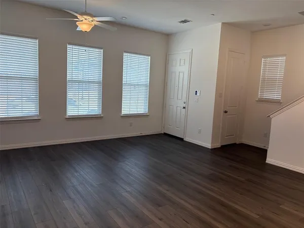 an empty room with wooden floor and windows