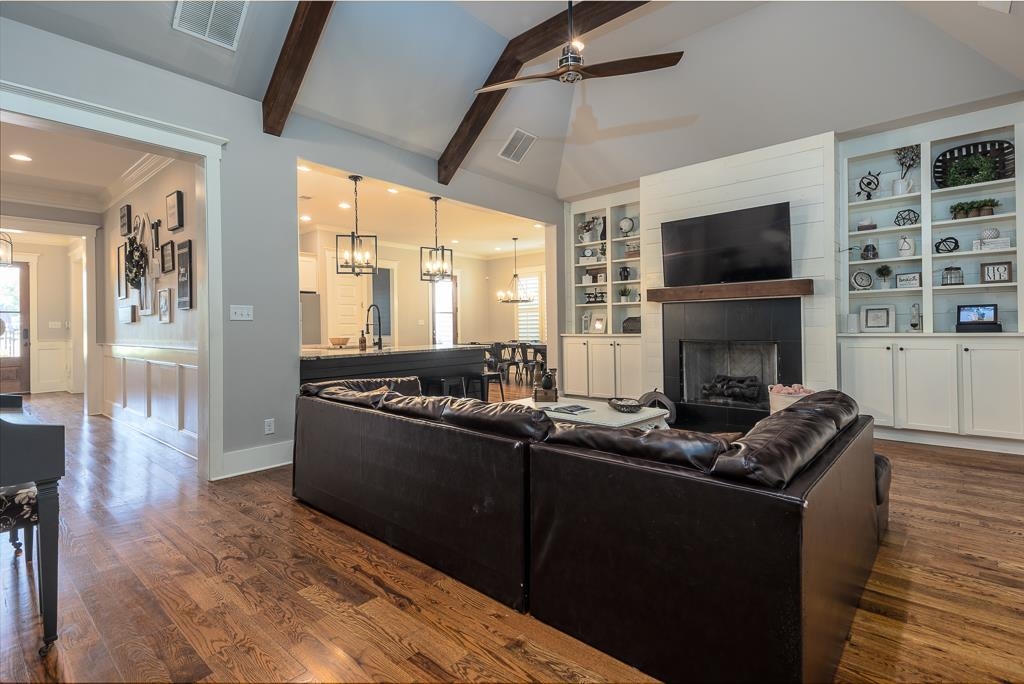 328 Washington Street Collierville, TN 38017 - Photo 8 of 33 Spacious living area featuring high vaulted ceilings with exposed wood beams, wood-finish flooring, a fireplace with a dark surround and wood mantel, and built-in shelving with lower cabinetry