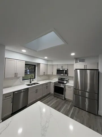 a kitchen with granite countertop a sink stainless steel appliances and cabinets