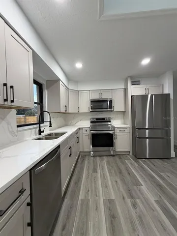 a large kitchen with a sink stainless steel appliances and cabinets