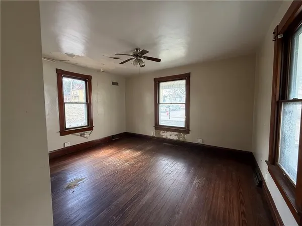 an empty room with wooden floor and windows