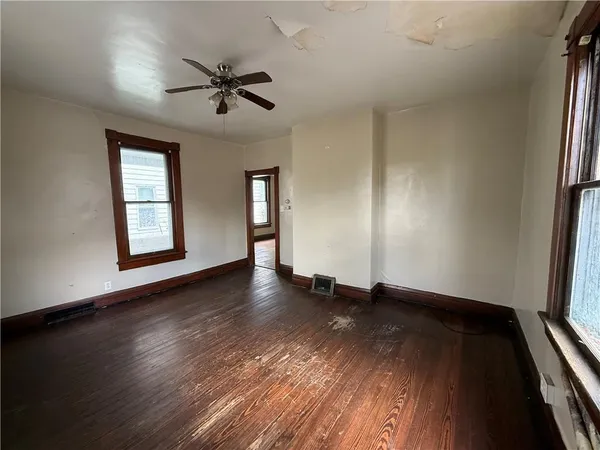 an empty room with wooden floor window and ceiling fan