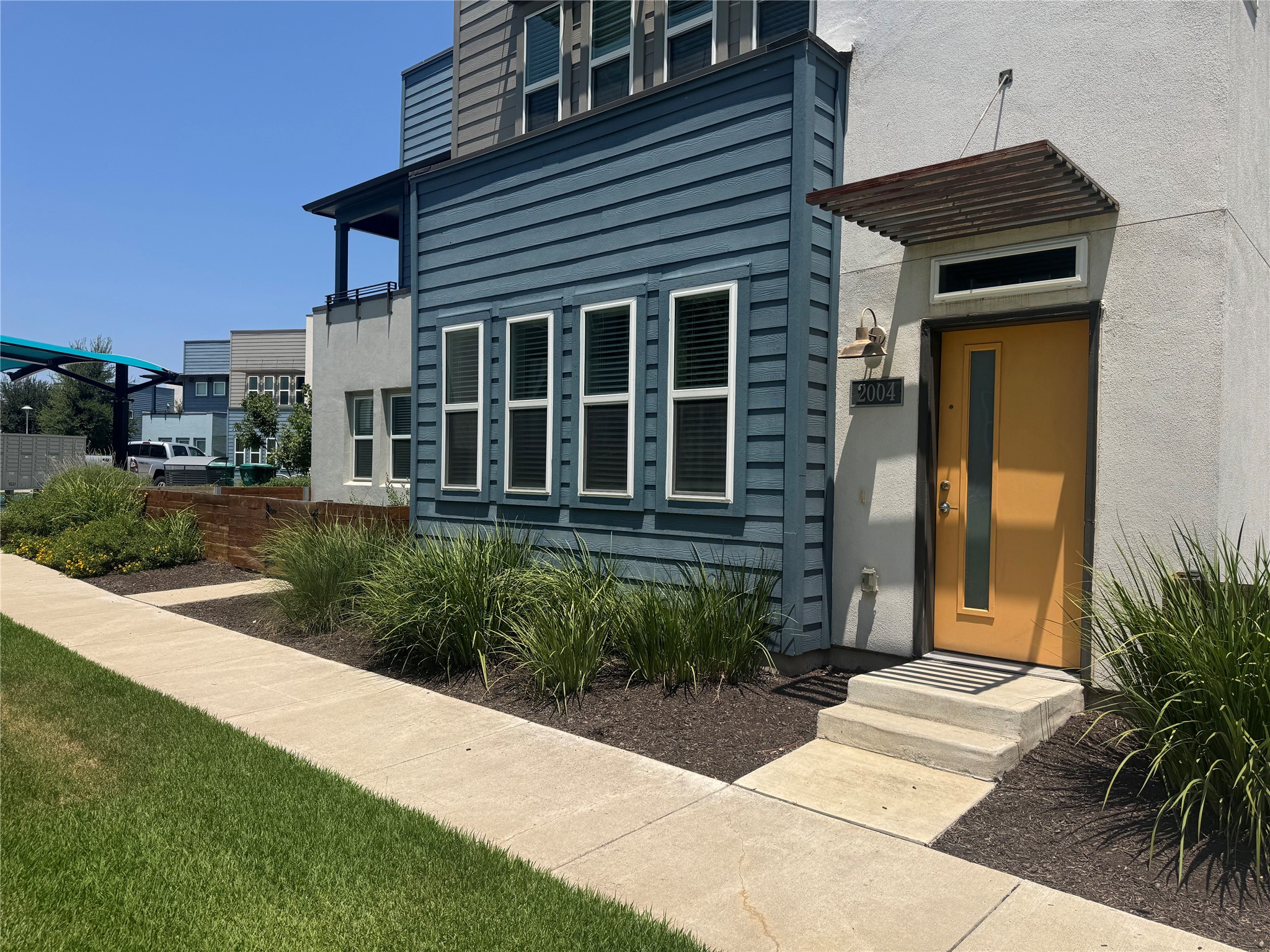 9015 Cattle Baron Path, Unit 2004 Austin, TX 78747 - Photo 1 of 27 A modern facade with striking blue siding and a welcoming yellow entry.