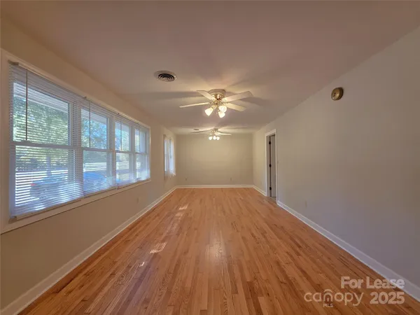 a view of empty room with wooden floor and fan