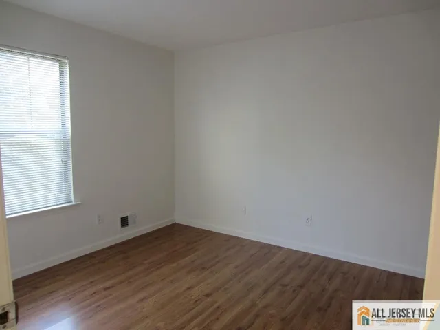 an empty room with wooden floor and window