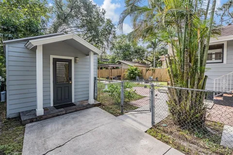 a view of a wooden house with a small yard and large tree