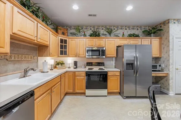 a kitchen with stainless steel appliances granite countertop a refrigerator a stove top oven a sink and dishwasher
