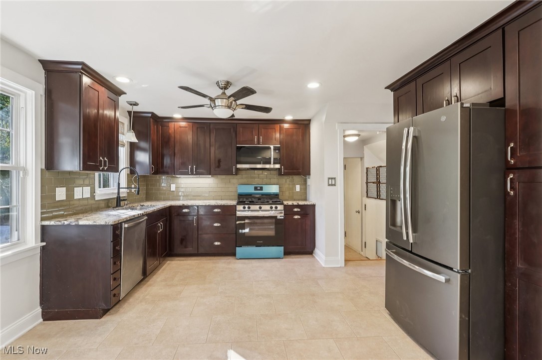 1151 Croyden Road Lyndhurst, OH 44124 - Photo 15 of 37 Kitchen featuring appliances with stainless steel finishes, decorative backsplash, pendant lighting, dark brown cabinetry, and light stone counters