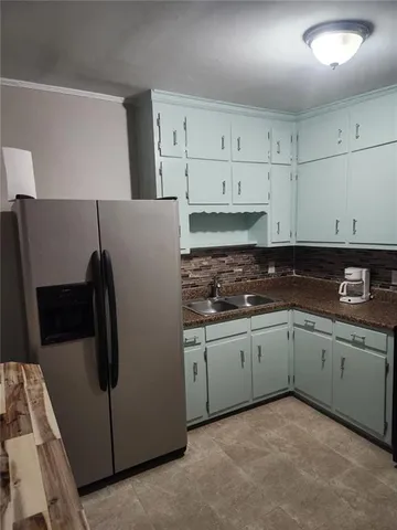 a kitchen with granite countertop white cabinets and refrigerator