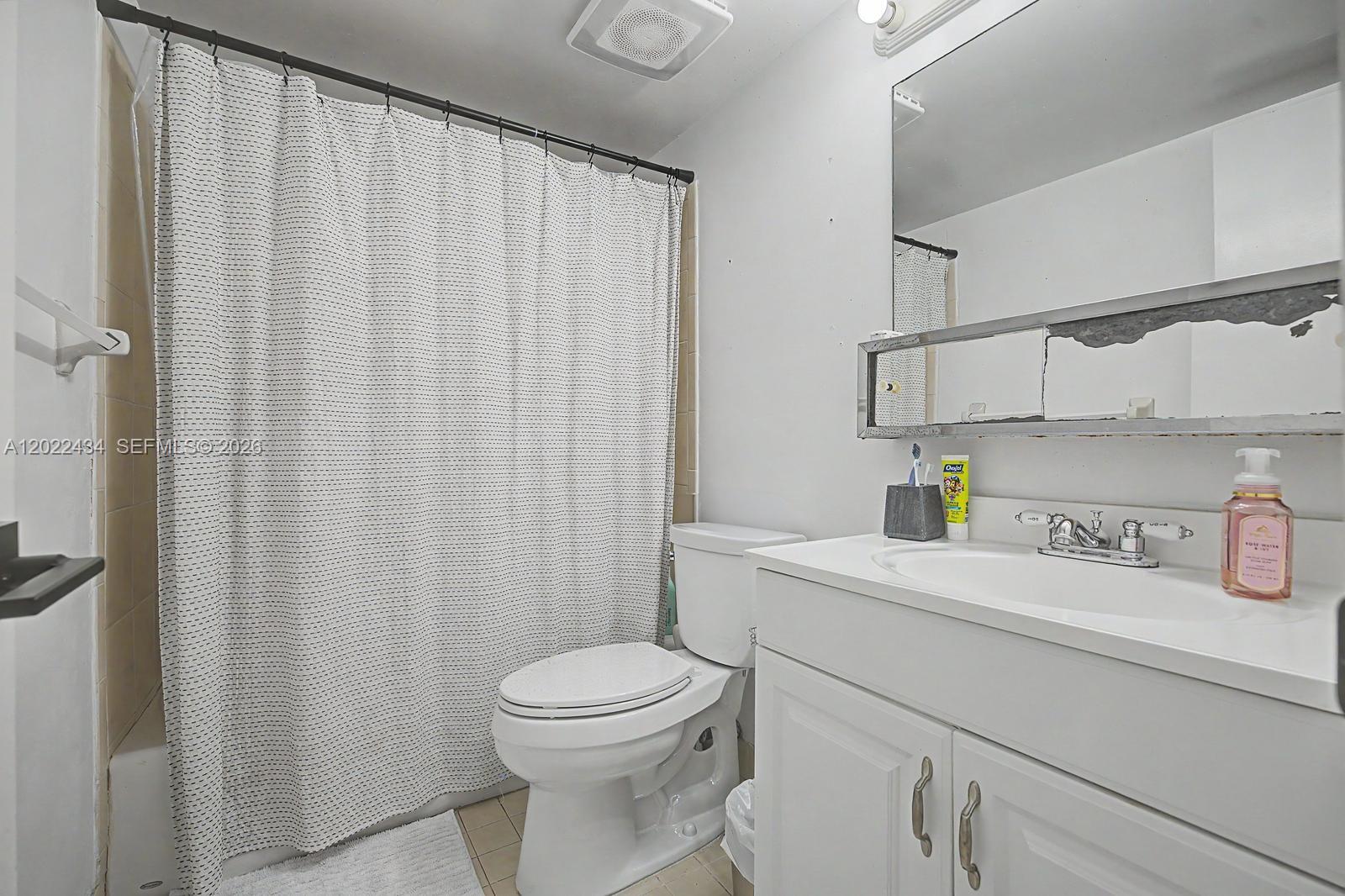 13045 Southwest 68th Street, Unit 111 Miami, FL 33183 - Photo 12 of 15 a bathroom with a sink a toilet and shower curtain