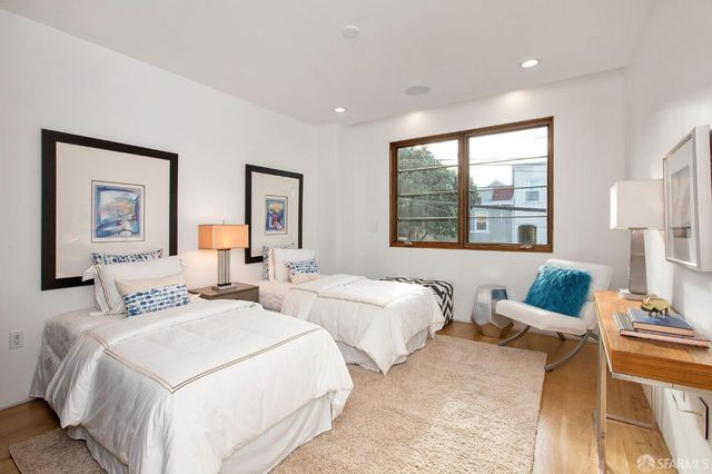 a bedroom with two beds and a large mirror next to a window