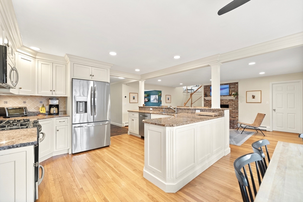 21 Batchelder Road Boxford, MA 01921 - Photo 4 of 37 a kitchen with stainless steel appliances kitchen island granite countertop a refrigerator a stove a sink a dining table and chairs with wooden floor