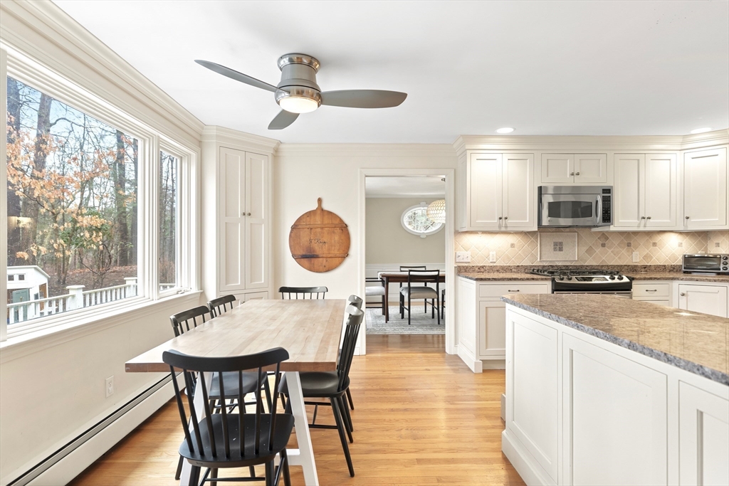 21 Batchelder Road Boxford, MA 01921 - Photo 6 of 37 a kitchen with stainless steel appliances kitchen island granite countertop a stove a sink dishwasher a dining table and chairs with wooden floor