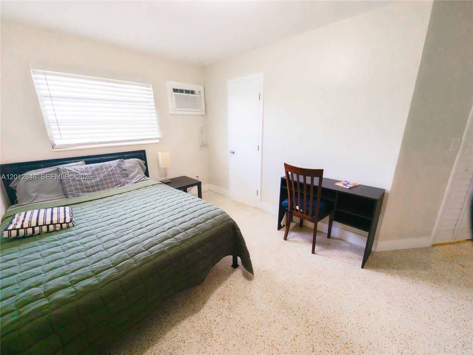 1220 Southwest 5th Street, Unit 16 Miami, FL 33135 - Photo 6 of 8 a bedroom with a bed wooden floor and a window