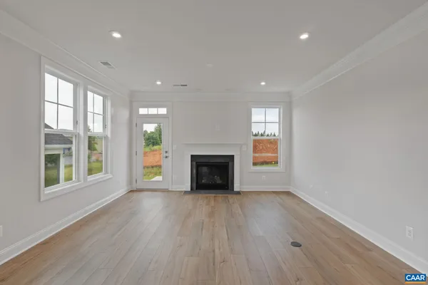 an empty room with wooden floor fireplace and windows
