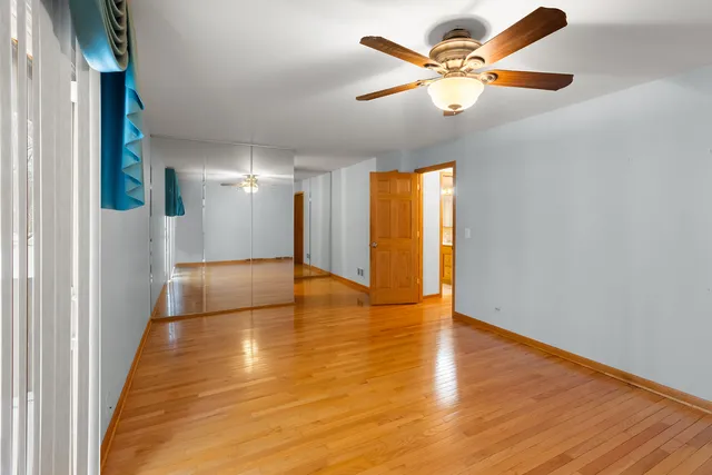 a view of an empty room with a window and wooden floor