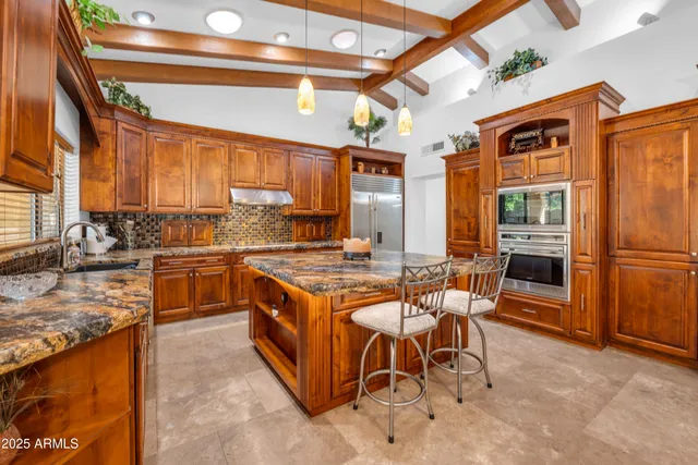 a kitchen with stainless steel appliances granite countertop a stove top oven a sink dishwasher a dining table and chairs with wooden floor