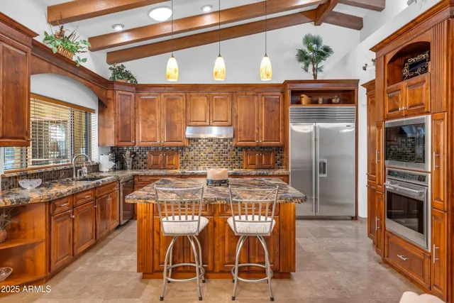 a kitchen with stainless steel appliances kitchen island granite countertop a refrigerator and a stove top oven