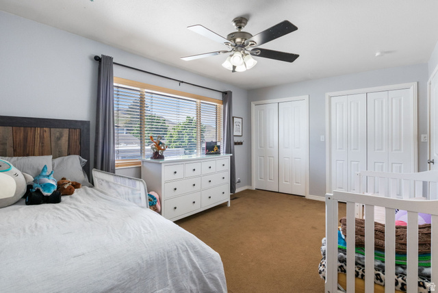 41 Benchmark Village Tooele, UT 84074 - Photo 14 of 26 Bedroom with two closets, dark colored carpet, and a ceiling fan