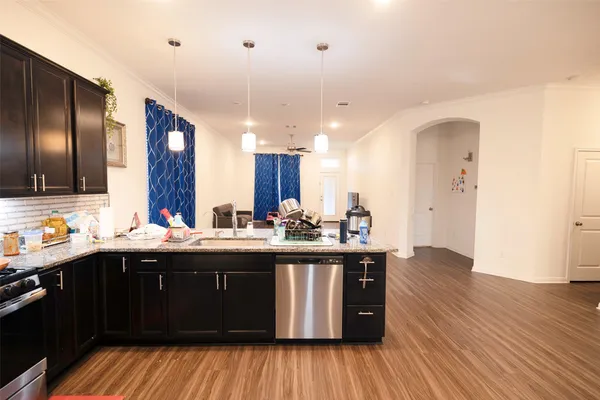 a kitchen with stainless steel appliances granite countertop a sink cabinets and wooden floor
