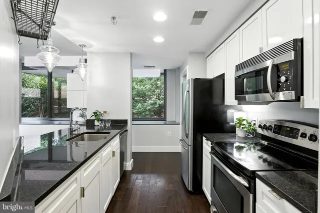 a kitchen with stainless steel appliances granite countertop a stove refrigerator and microwave