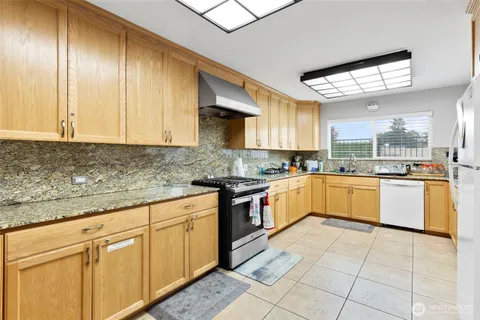 a large kitchen with stainless steel appliances granite countertop a stove sink and cabinets