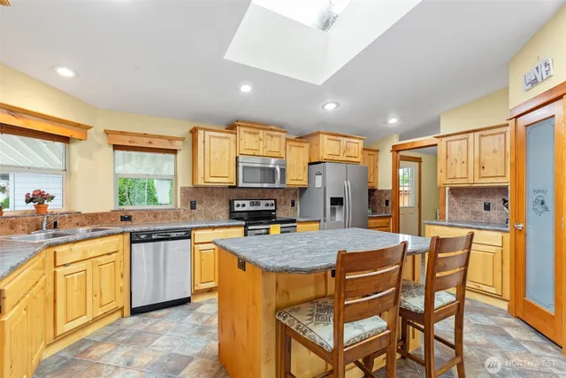 a kitchen with stainless steel appliances granite countertop table chairs sink and cabinets