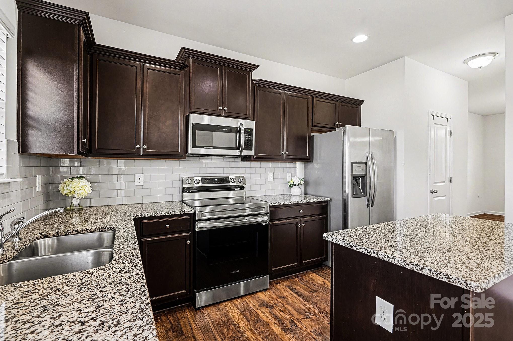 3224 Hawksbill Street Southwest Concord, NC 28027 - Photo 9 of 35 a kitchen with granite countertop stainless steel appliances and wooden cabinets