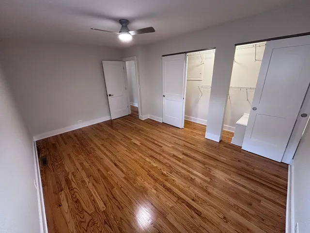a view of empty room with wooden floor and fan