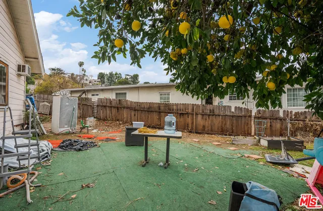 a view of a backyard with couches table and chairs and potted plants