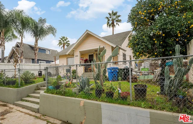 a view of a house with a small yard plants and a large tree