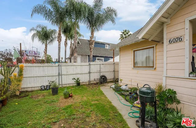 a backyard of a house with potted plants and palm tree