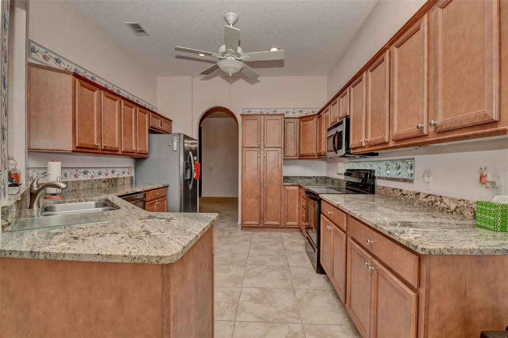 58 Byrsonima Loop Homosassa, FL 34446 - Photo 19 of 43 a kitchen with stainless steel appliances granite countertop a sink dishwasher stove and refrigerator with wooden cabinets