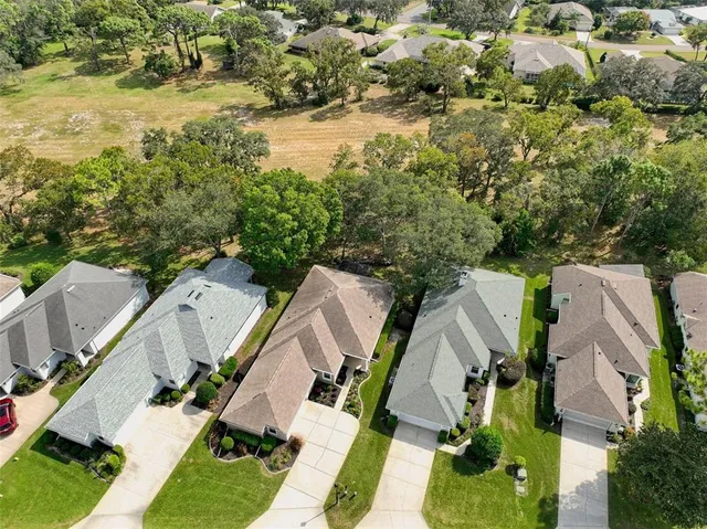 an aerial view of residential houses with outdoor space and trees