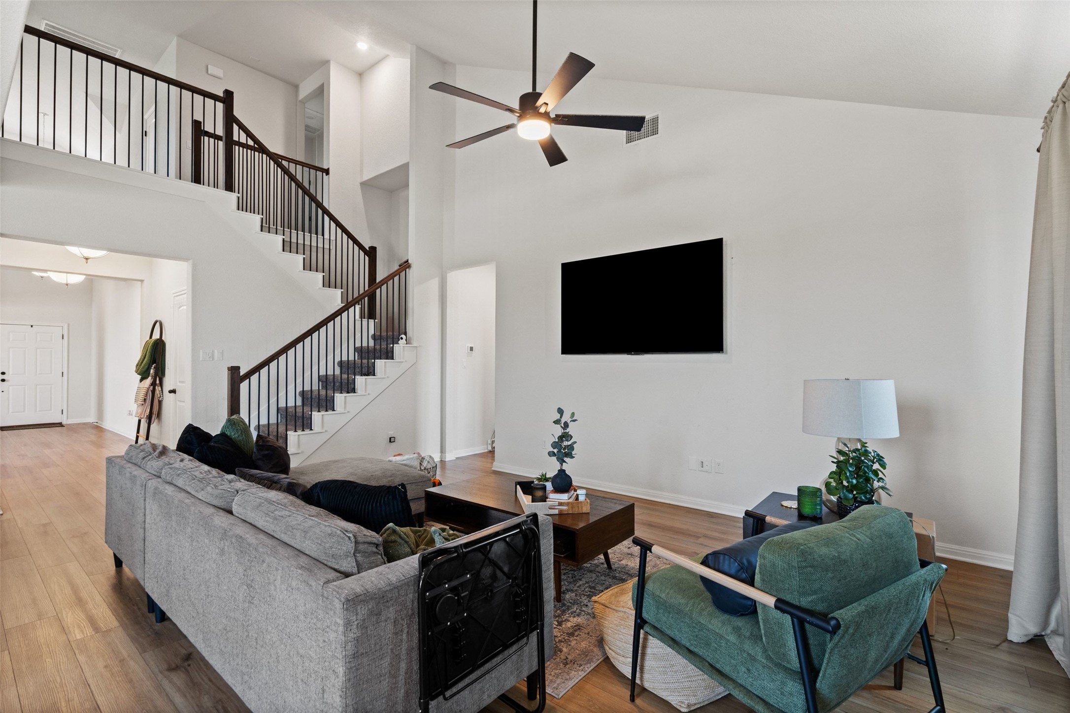 100 Panico Road Hutto, TX 78634 - Photo 13 of 28 A spacious, naturally illuminated living room featuring high ceilings and elegant wood flooring.