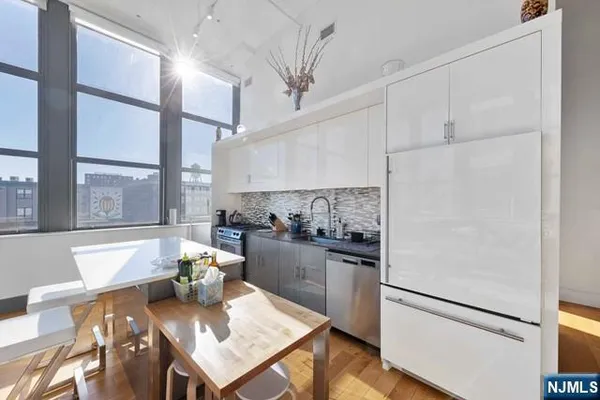 a kitchen with a refrigerator a stove and a dining table with wooden floor