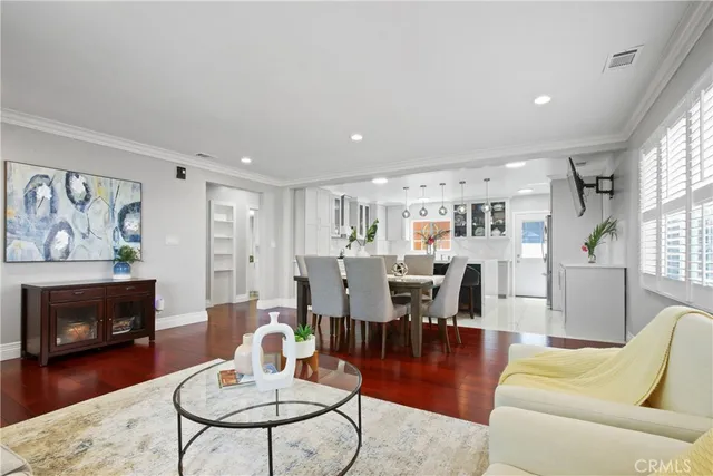 a living room with furniture kitchen view and a wooden floor