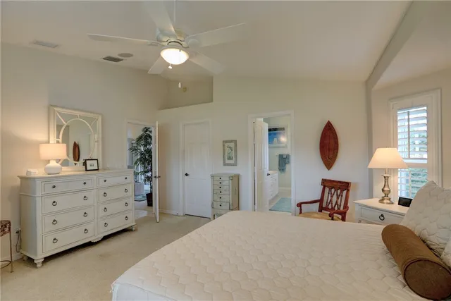 a bedroom with a bed a chandelier with a dresser and chair