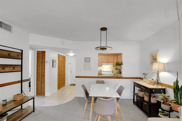 a kitchen with stainless steel appliances kitchen island a table chairs in it and a window