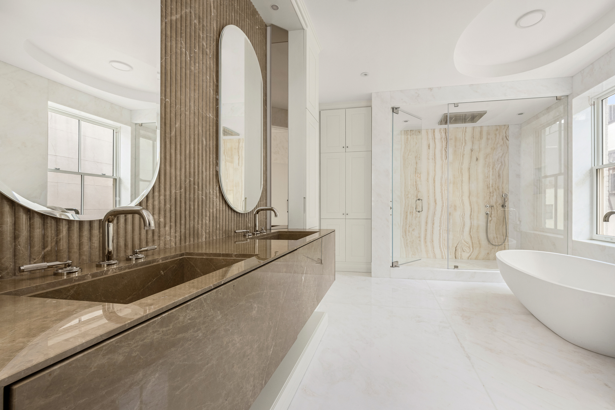 133 East 73rd Street, Unit 3 Manhattan, NY 10021 - Photo 6 of 12 a spacious bathroom with a mirror a bathtub and a shower