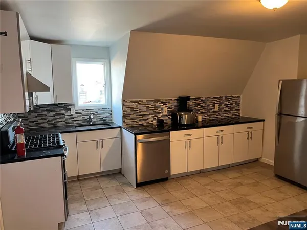 a kitchen with stainless steel appliances a refrigerator and white cabinets