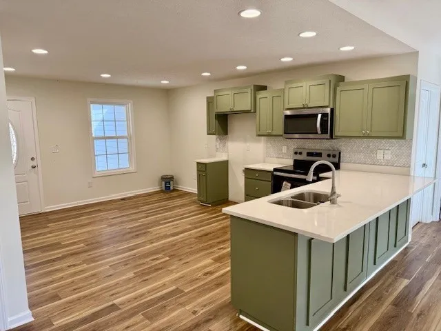 a kitchen with stainless steel appliances granite countertop a sink a stove top oven and wooden floors