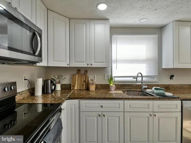 a kitchen with granite countertop a sink a stove and cabinets